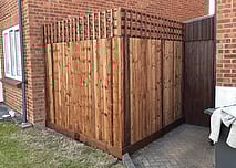 Image shows timber closeboard fencing with integrtaed square section trellis fitted above. Built between two properties.
