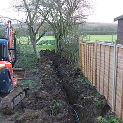 Image shows that we are laying a water pipe and mains power cable in a trench along the boundary line. At some point there is a plan for an outdoor shed and cooking area and power and water will be necessary.