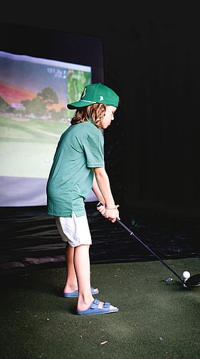 Young golfer practicing with a Daddy Shack mobile golf simulator