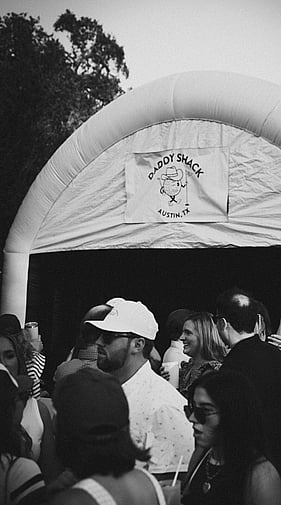 Crowd gathered around the Daddy Shack mobile golf simulator tent at an outdoor event