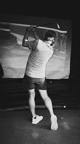 Golfer completing a full swing at a Daddy Shack mobile golf simulator event