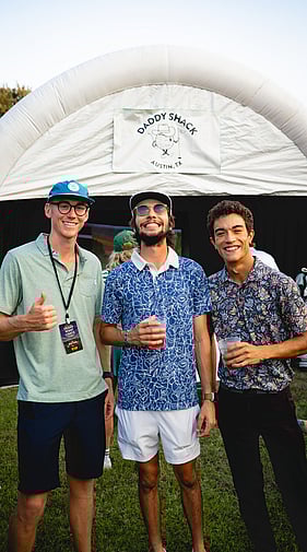 Three Daddy Shack staff members smiling at an outdoor golf event