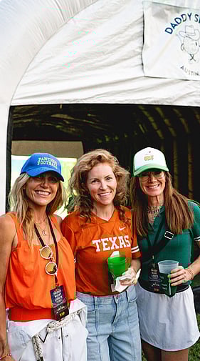 Three women posing together near the Daddy Shack tent at a golf event