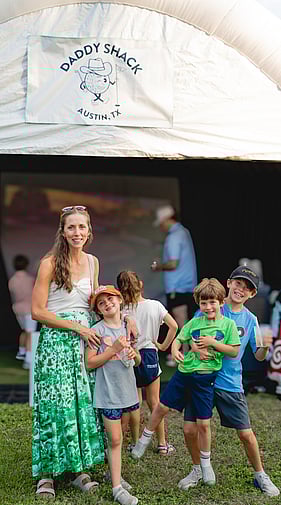 Woman and children posing together at an outdoor Daddy Shack golf event