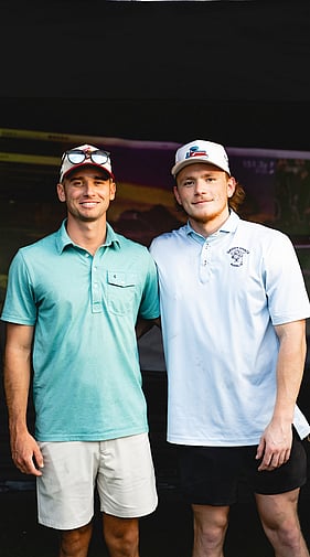 Two men smiling and posing at a Daddy Shack outdoor golf event