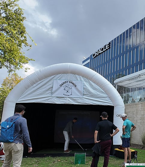 People watching man use mobile golf simulator