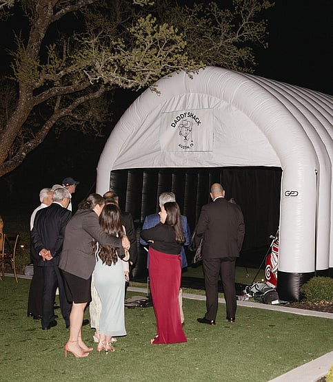 Wedding patrons socializing outside of mobile golf simulator
