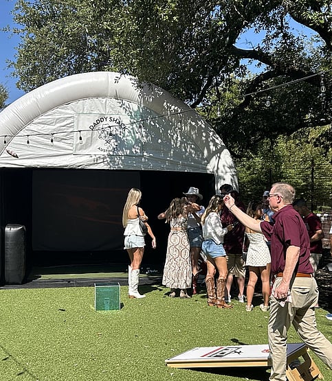 Man playing cornhole outside of the mobile golf simulator