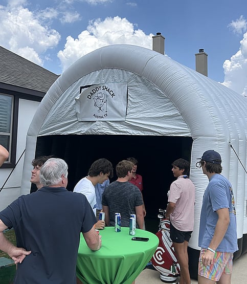 People socializing outside of mobile golf simulator