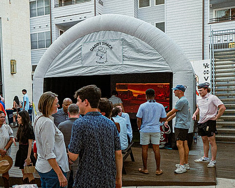 People socializing outside of the Daddy Shack mobile simulator
