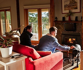couple and their dog sitting in the lounge with the fire