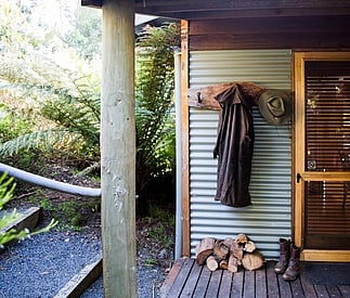 entry with logs for fire stacked with boots and coat