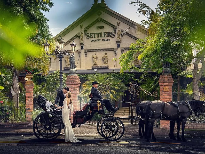 Wedding couple arriving by horse-drawn carriage at Settlers Country Manor, an Auckland wedding venue