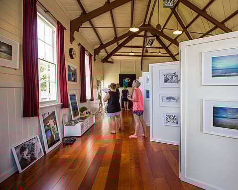3 people looking at art displayed in the Kūaotunu Hall