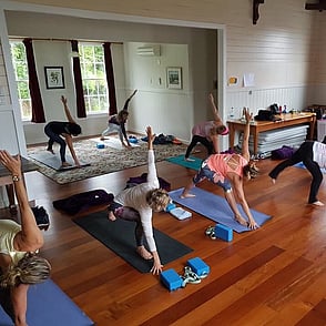 A group of people doing yoga on their yoga mats in the Kūaotunu Hall