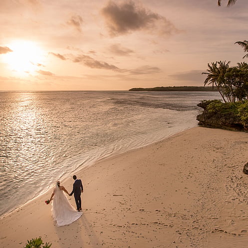 Couple walking along a secluded beach as part of a luxury destination wedding or honeymoon experience