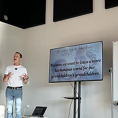 Nik Gregg cofounder presenting with a tv screen of a powerpoint next to him