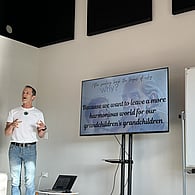 Nik Gregg cofounder presenting with a tv screen of a powerpoint next to him