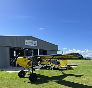 Small aircraft outside beside hangar