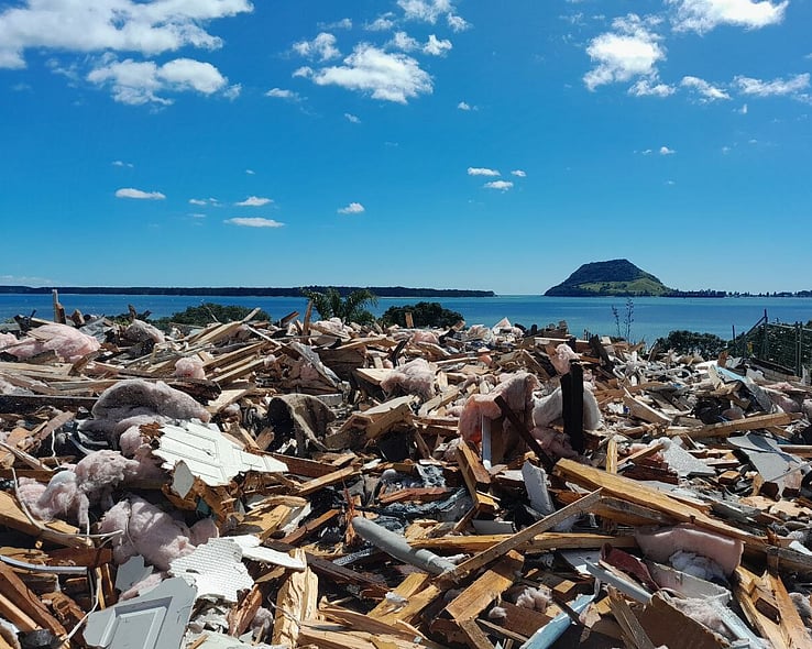 Sorted timber and insulation from a house demolition, with Mount Maunganui in the background
