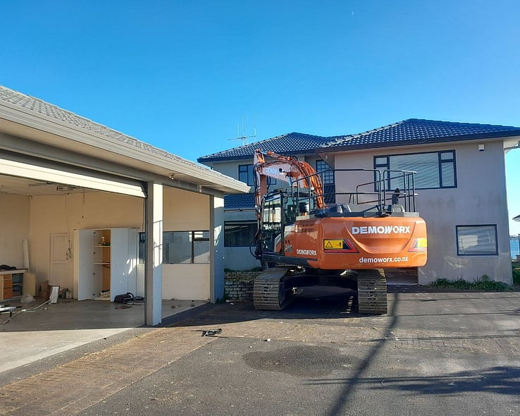 Demoworx excavator in the driveway of a two-storey house before demolition