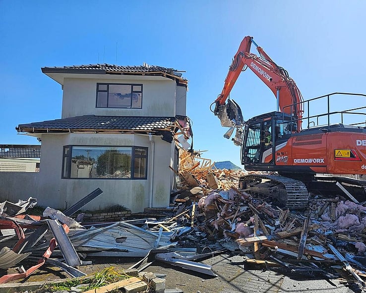 Excavator demolishing a two-storey house