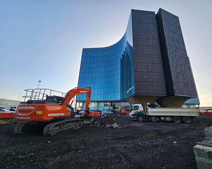Demoworx excavators clearing a site next to a curved glass building