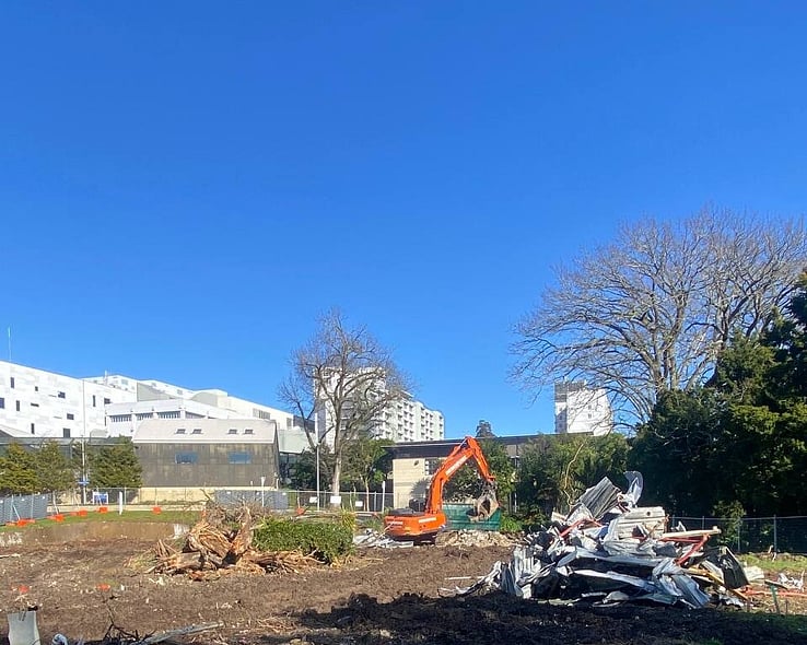 Cleared site with an excavator sorting the last of the debris