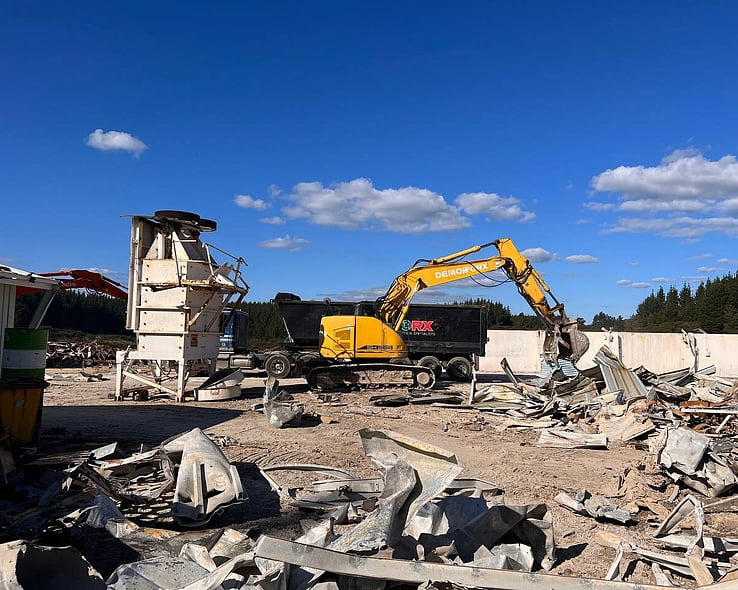 Demolition of an industrial building with an excavator on the rubble