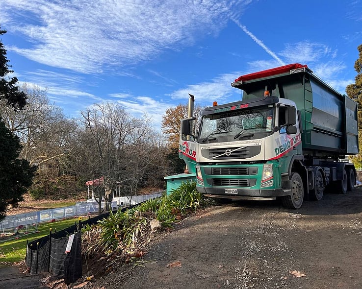 Demoworx bin truck on a site beside a stream