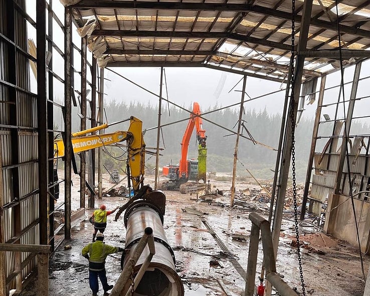 Workers and machinery inside an industrial building being stripped out