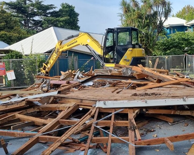 Small excavator demolishing a timber building