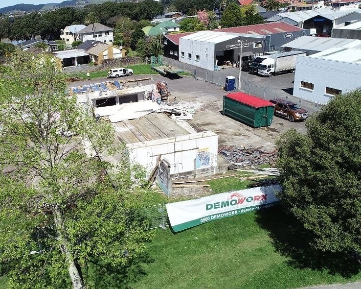 Aerial view of a cleared site with a Demoworx banner on the fence