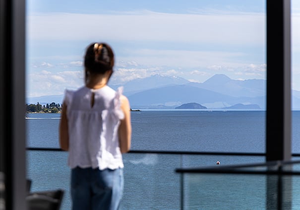 Guest taking in the lake and mountain views from inside a Roam Taupo unit