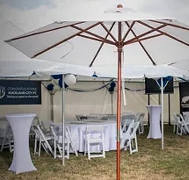 Patio umbrellas with wooden poles next to marquee &ndash; stylish outdoor shading solutions NZ