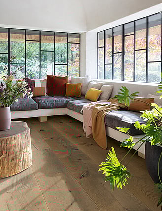 Rustic timber flooring in a modern lounge with large windows.