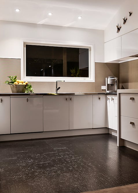 Brown leather flooring in a white kitchen.