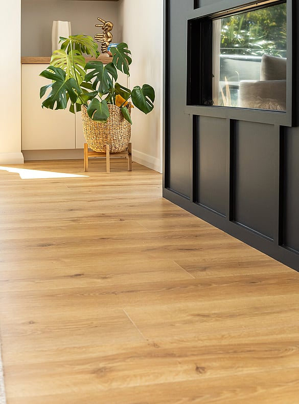 A light beige laminate floor in a kitchen, dining room and living area. Living area has a bright yellow couch. 