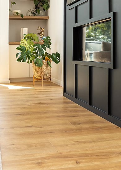 A black fireplace with wood look laminate flooring in natural tones. 