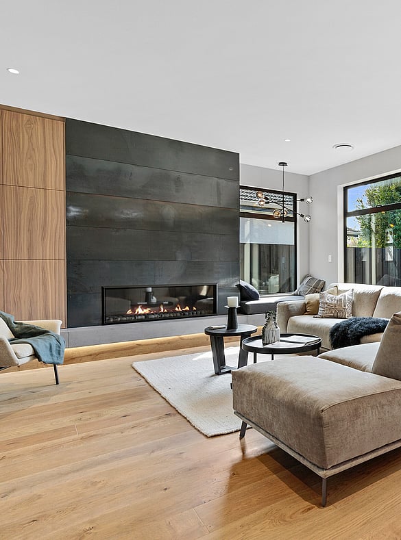 A black fireplace and open plan living area with natural wood flooring.