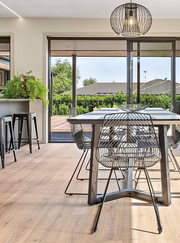 Open plan kitchen and dining room with light brown laminate flooring.