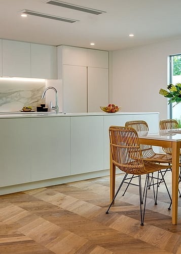 Chevron oak flooring and a pale green kitchen creates a neutral interior design style. 