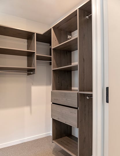 Brown wood fitted wardrobe with drawers, hanging rails and solid shelves.