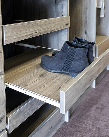 Black shoes on a wardrobe shoe shelf.