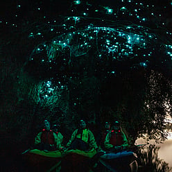 Small group sitting in kayaks below glow worms