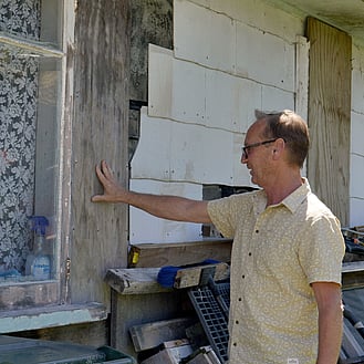 Person looking at side of house with exposed wood