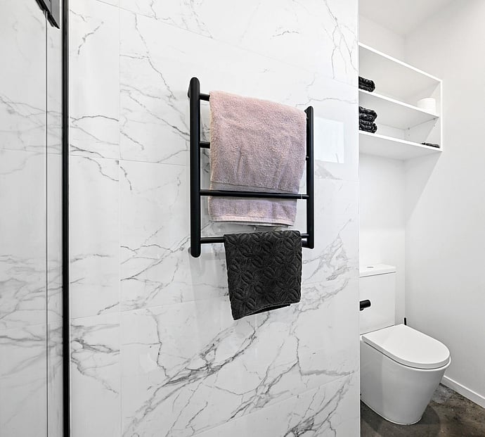 A well built bathroom with white marble tile and black accessories 