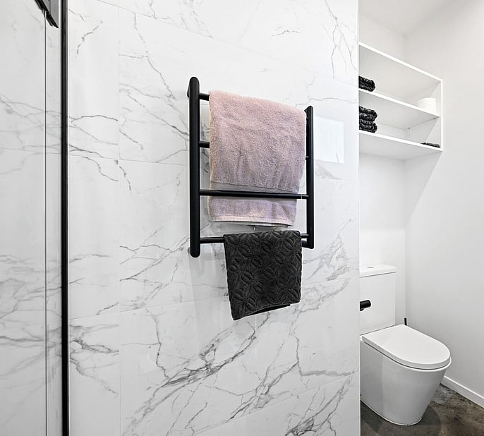 A well built bathroom with white marble tile and black accessories 