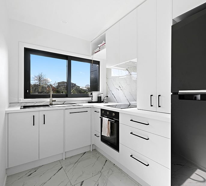 A stylish small kitchen, well designed to fit a granny flat, white marble tile, white kitchen cabinetry