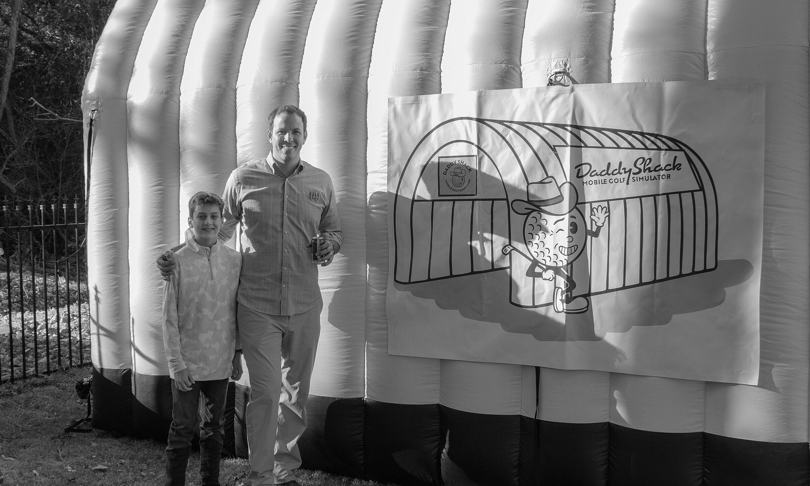 Man and son posing in front of Daddy Shack's golf simulator